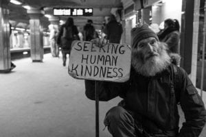 Nonprofit Business work for the betterment of society or a select group of people such as this homeless man who is holding sign reading Seeking Human Kindness