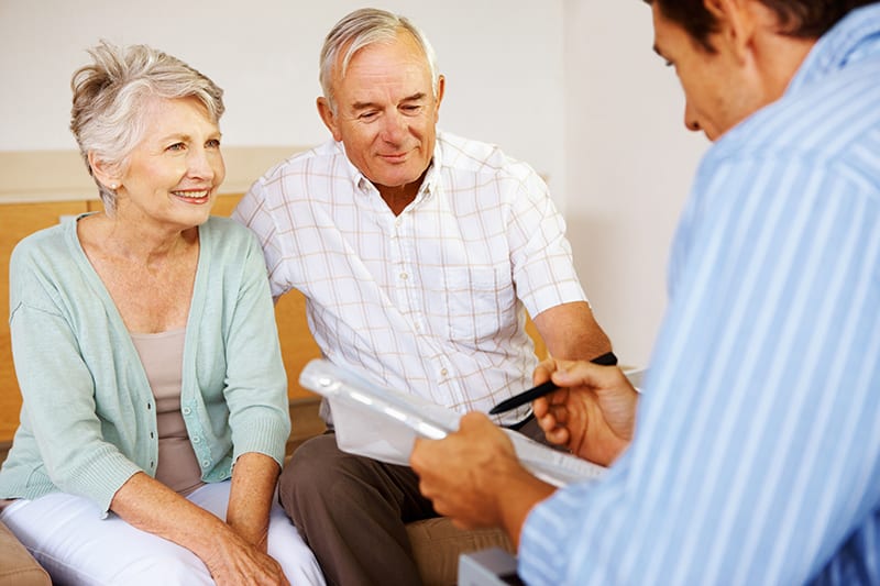 Photo of elderly couple talking to attorney about estate planning