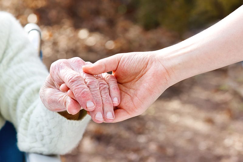 Photo of young woman holding senior lady hand